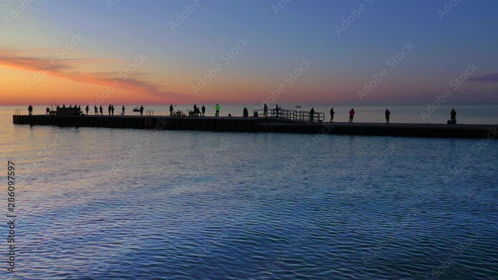 Many people fishing on pier before sunrise, silhouetted in twilight. Many people fishing on pier before sunrise, silhouetted in twilight.