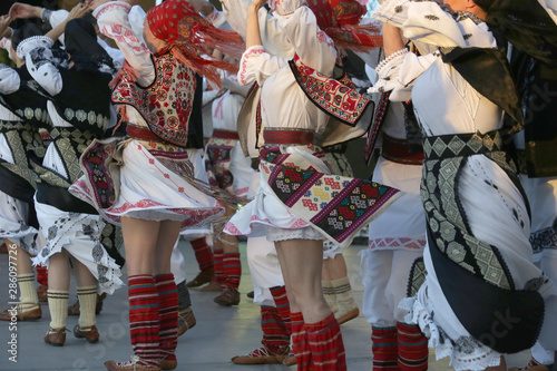 Professional dancers of the Timisul Folklore Ensemble hold hands in a traditional Romanian dance wearing traditional beautiful costumes. photo