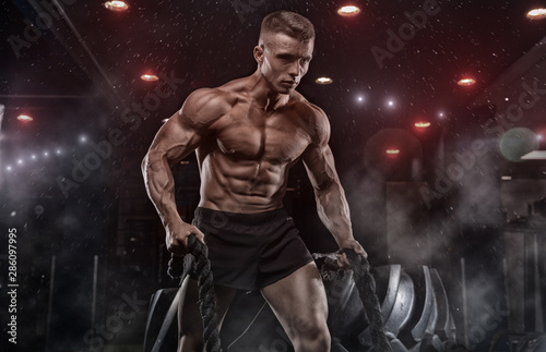 Male athlete bodybuilder posing on a black background