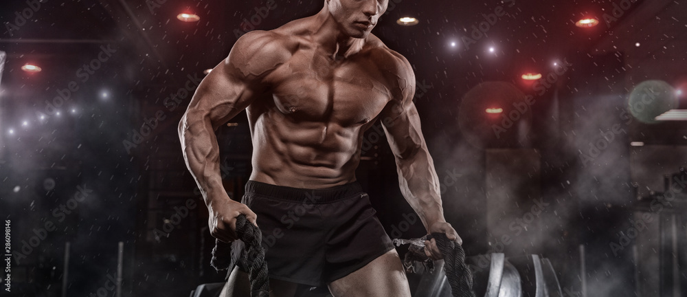 Male athlete bodybuilder posing on a black background - obrazy, fototapety, plakaty 