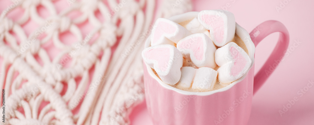 Cup of hot chocolate with pink heart shaped marshmallows and macrame panel on pink background, trendy minimal romantic composition, saint valentine morning, banner Cup of hot chocolate with pink heart shaped marshmallows and macrame panel on pink background, trendy minimal romantic composition, saint valentine morning, banner