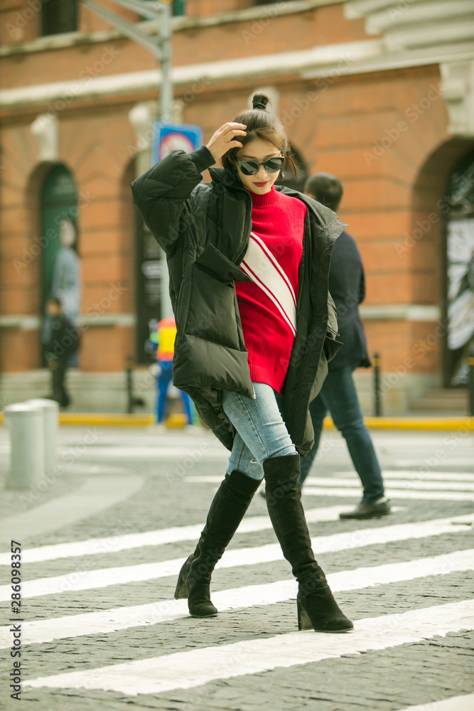 Stylish Asian girl wearing long black down jacket on the street