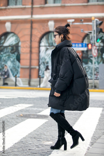 Stylish Asian girl wearing long black down jacket on the street