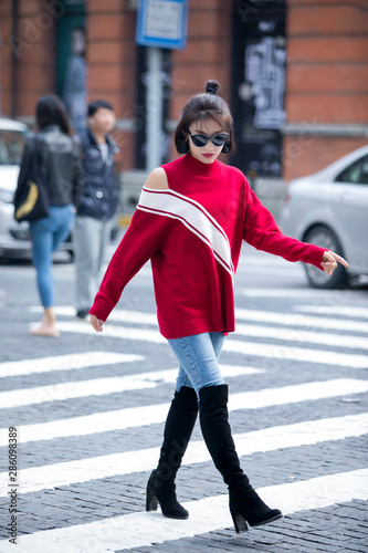 Asian girl in red sweater with bare shoulders fashion walking on the streets of Shanghai