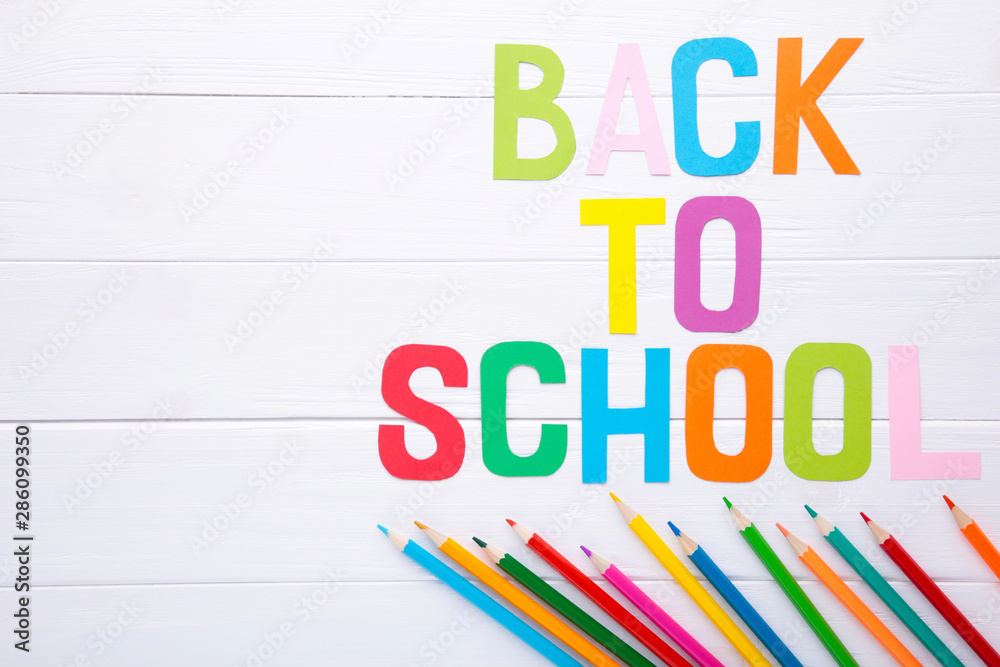 Inscription Back To School with school supplies on white wooden background