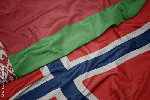 waving colorful flag of norway and national flag of belarus.