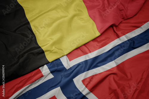 waving colorful flag of norway and national flag of belgium.