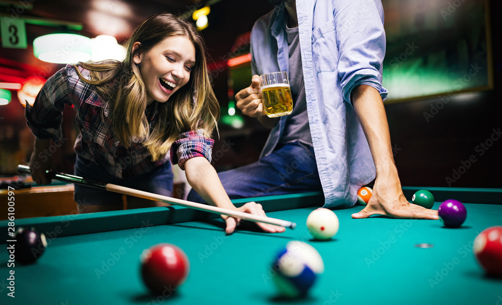 Fototapeta premium Young couple playing snooker together in bar