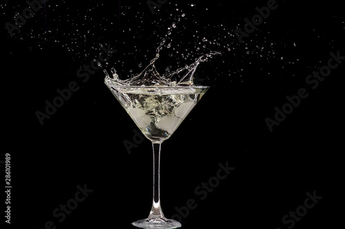glass of martini and splash from falling ice on a black background