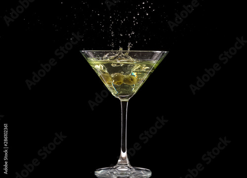 a glass of martini and a splash from falling olives