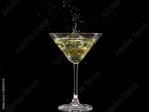 a glass of martini and a splash from falling olives