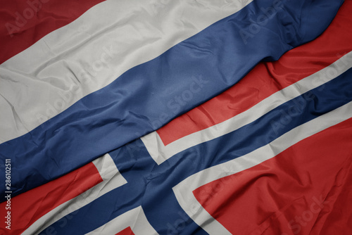waving colorful flag of norway and national flag of netherlands.