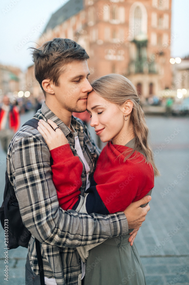 Fototapeta premium Young loving couple hugs at central square in Krakow (Cracow).