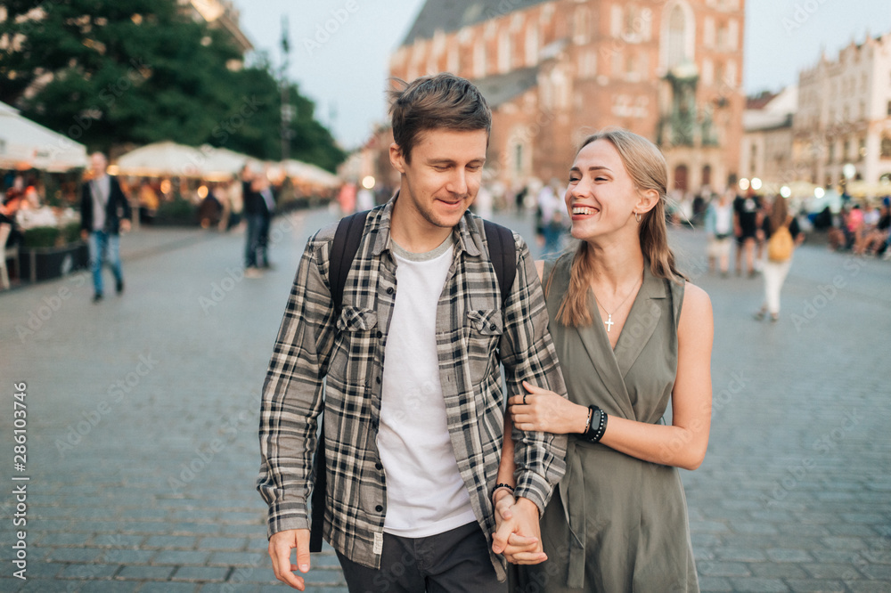 Fototapeta premium Happy loving couple smiling and walking throug the main square in Krakow (Cracow)