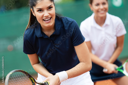 Young happy fit women playing tennis on tennis court
