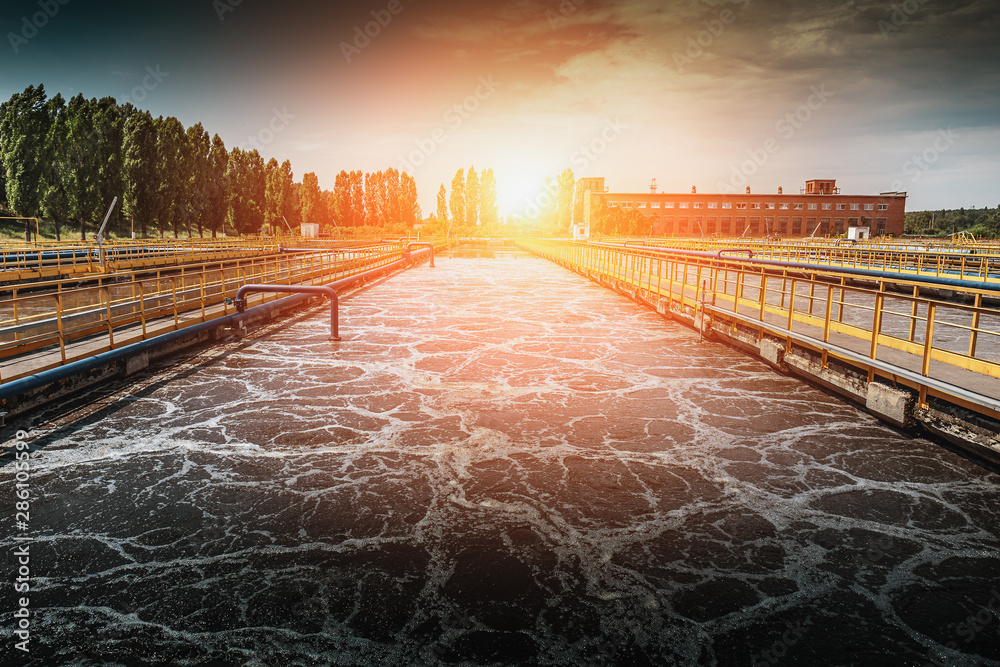 Wastewater treatment plant at sunset. Tanks for aeration and cleaning of sewage mass - obrazy, fototapety, plakaty 