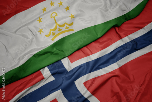 waving colorful flag of norway and national flag of tajikistan.