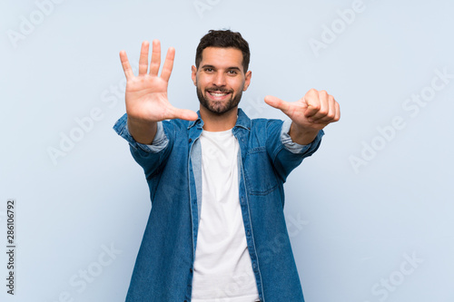 Handsome man over isolated blue background counting six with fingers © luismolinero