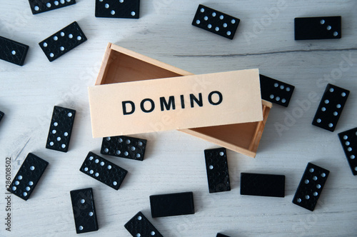 Closeup scattered dominoes on a gray, wooden table. Board game.