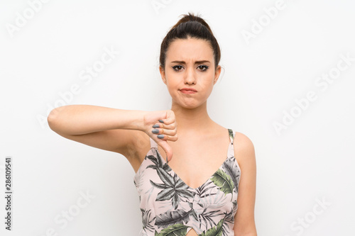 Young woman over isolated white background showing thumb down sign