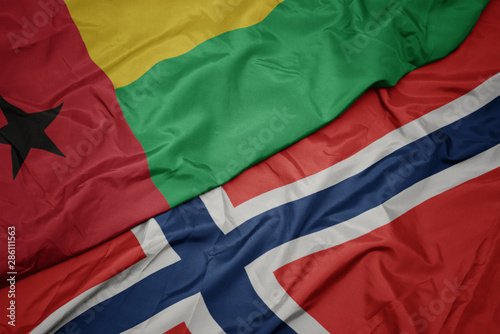 waving colorful flag of norway and national flag of guinea bissau.