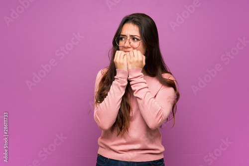 Fotografía Teenager girl over purple wall nervous and scared putting hands to mouth