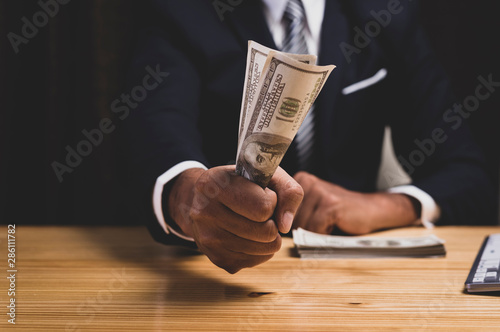 Asian businessman hand grabbing money hundred dollar bills for corruption each other as a reward.,corruption concept.