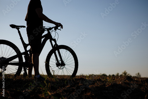Fototapeta Naklejka Na Ścianę i Meble -  The silhouette of a bicycle and rider against the blue sky at sunset