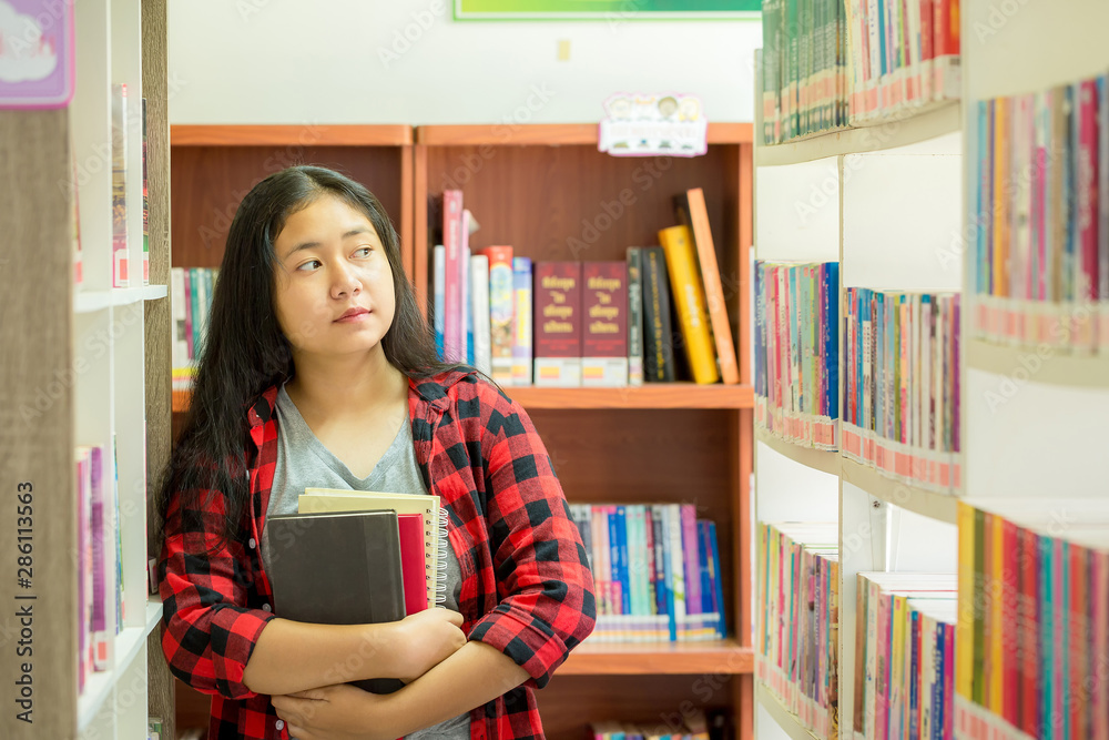 Portrait of clever student with open book reading it in college library Portrait of clever student with open book reading it in college library