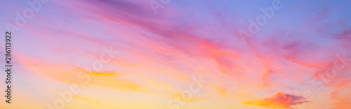 Panorama of the sunset sky with pink and golden layered clouds. Natural heaven background. Beautiful skyscape photo