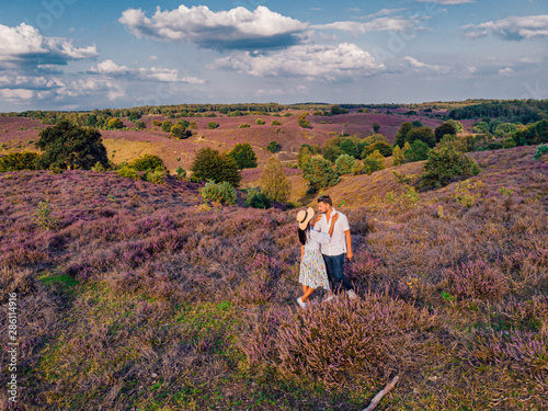 young couple men and woman hiking in the hills of the blooming heather field by the Posbank Veluwezoom Netherlands photo