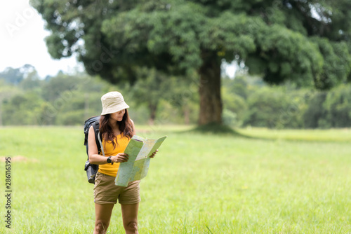 Women hiker or traveler with backpack adventure holding map to find directions and walking relax in the jungle forest outdoor for destination leisure education nature on vacation. Travel Lifestyle