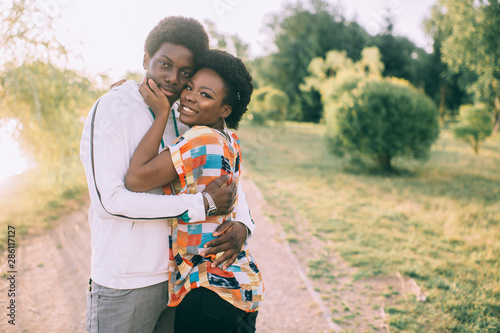Konstfotografi Happy dark skinned couple with sincere emotional feelings hugs outdoor at nature