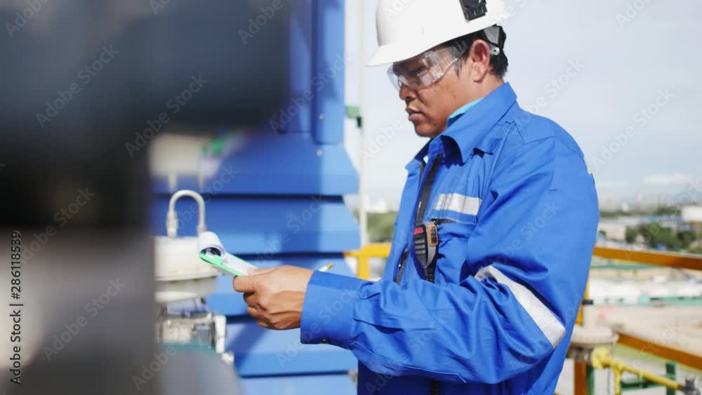 Close up of Engineer on site checking instrument equipment and record on paper clipboard , Oil and gas petroleum refinery plant working concept Close up of Engineer on site checking instrument equipment and record on paper clipboard , Oil and gas petroleum refinery plant working concept