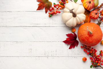 Festive autumn decor from pumpkins, berries and leaves on a white  wooden background. Concept of Thanksgiving day or Halloween. Flat lay autumn composition with copy space.