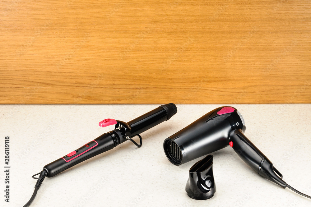 Hair iron and dryer on woody marbled background with copy space