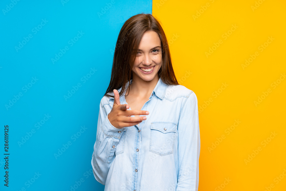 Young woman over colorful background points finger at you Young woman over colorful background points finger at you