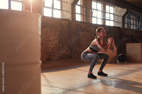 Fitness workout. Sport woman doing squat leg exercise at gym