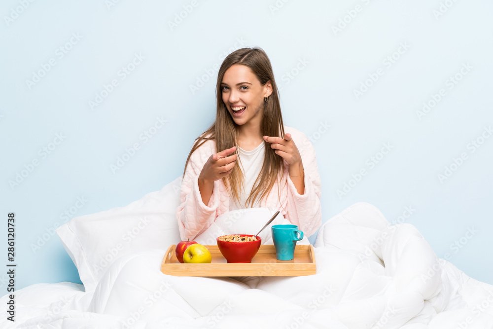Young woman in dressing gown with breakfast points finger at you