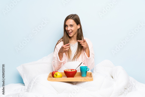 Young woman in dressing gown with breakfast points finger at you