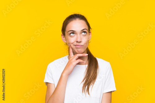 Foto Young woman over isolated yellow background thinking an idea
