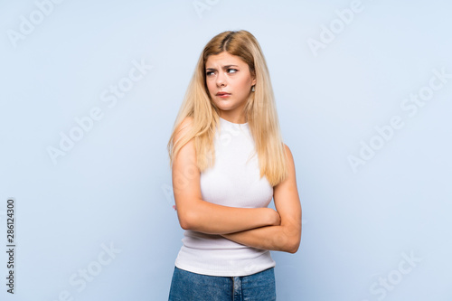Teenager girl over isolated blue background sending a message with the mobile
