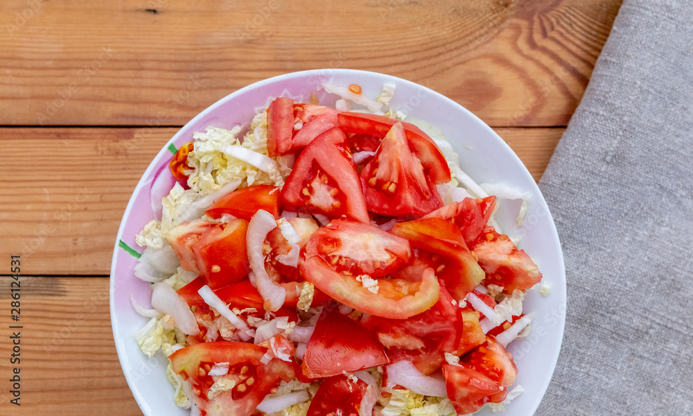 Sliced tomatoes, onions and cabbage on a plate on the table. Sliced tomatoes, onions and cabbage on a plate on the table.