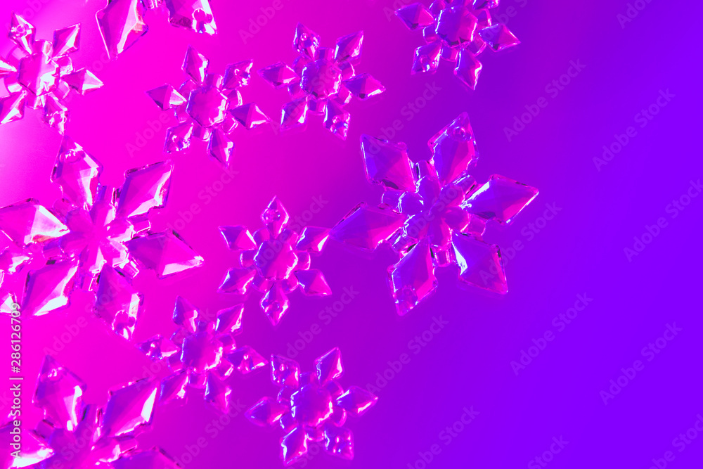Clear glass snowflakes in neon light sparse on gradient purple and pink background. Minimal christmas concept. Open composition. Copy space for text. Flat lay style.