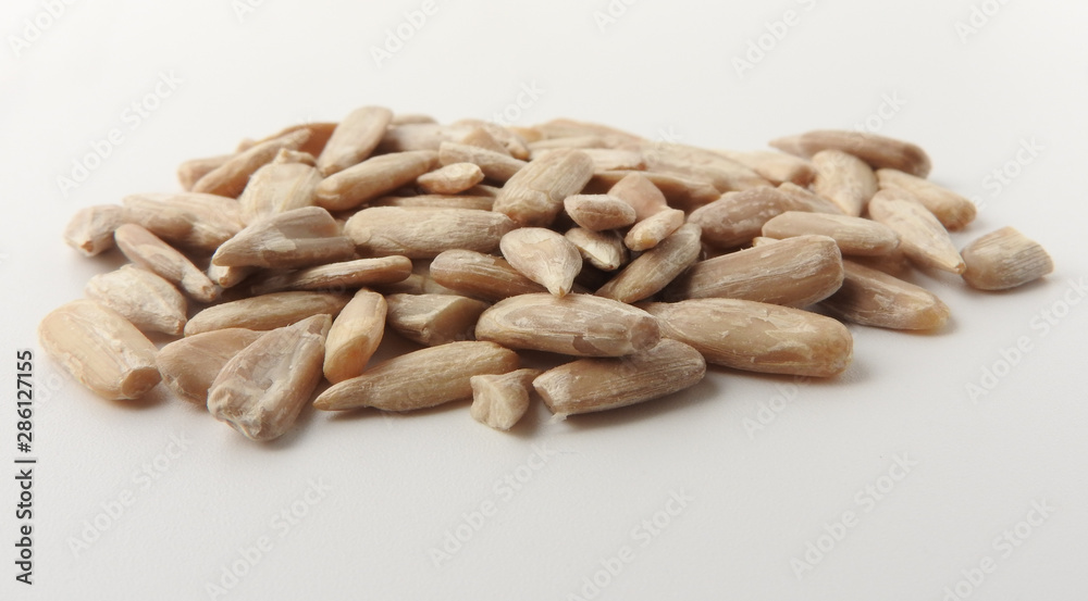 Front view of a pile of natural shelled organic sunflower seeds isolated on white background. It often eaten as a snack. The seeds contain vitamin E. Food and snack concept. With copy space. Front view of a pile of natural shelled organic sunflower seeds isolated on white background. It often eaten as a snack. The seeds contain vitamin E. Food and snack concept. With copy space.