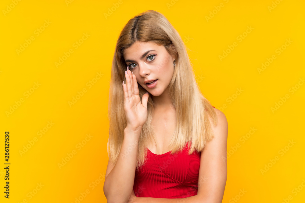 Teenager girl over isolated yellow background whispering something Teenager girl over isolated yellow background whispering something