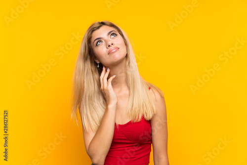 Teenager girl over isolated yellow background thinking an idea