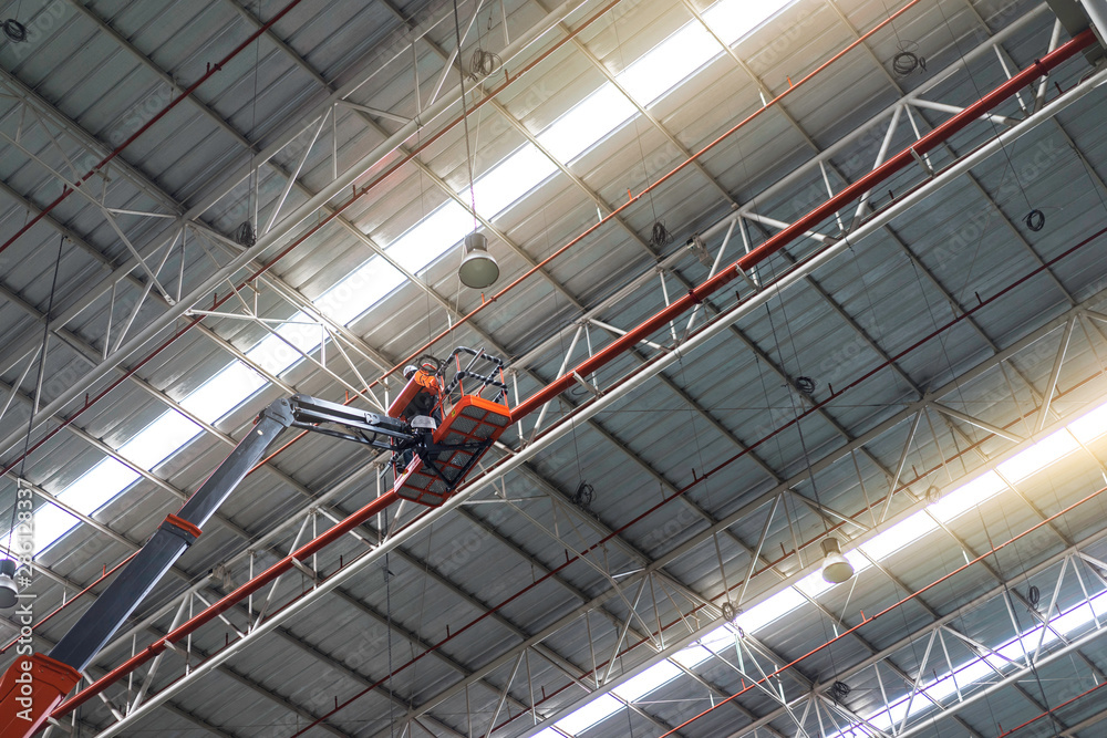 Worker standing on an articulating boom lifts in the factory.
