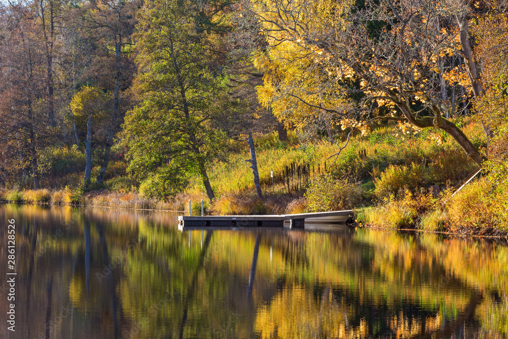 Jetty on the beach and reflections of autumn colors in the water Jetty on the beach and reflections of autumn colors in the water