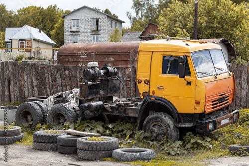 An old big yellow truck without a trailer during a repair or breakdown in the backyard of the village. Equipment for agriculture. © Aleksandr Kondratov